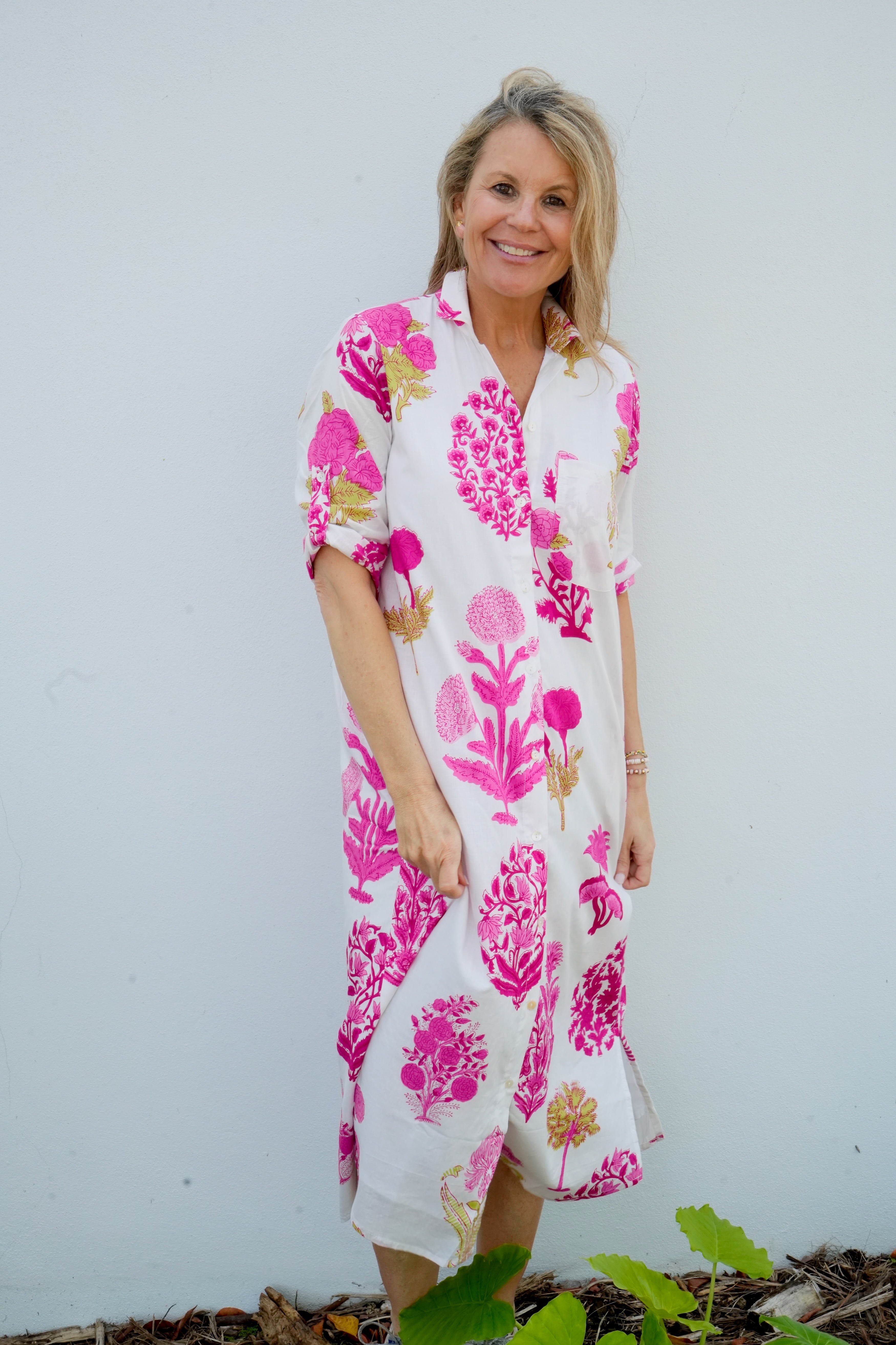 Woman wearing a white dress with pink floral pattern against a plain background
