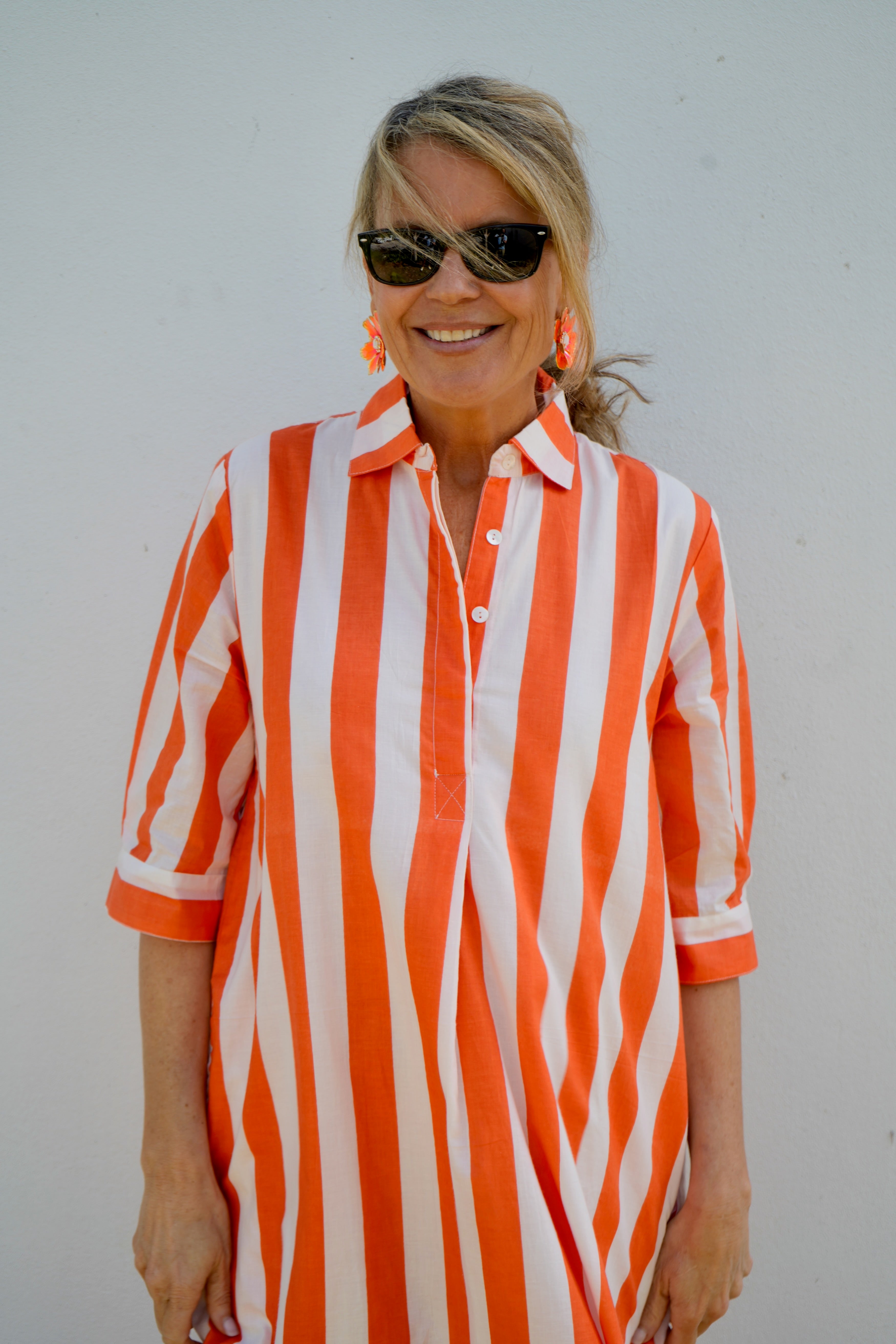 Woman wearing an orange and white striped shirt against a plain background