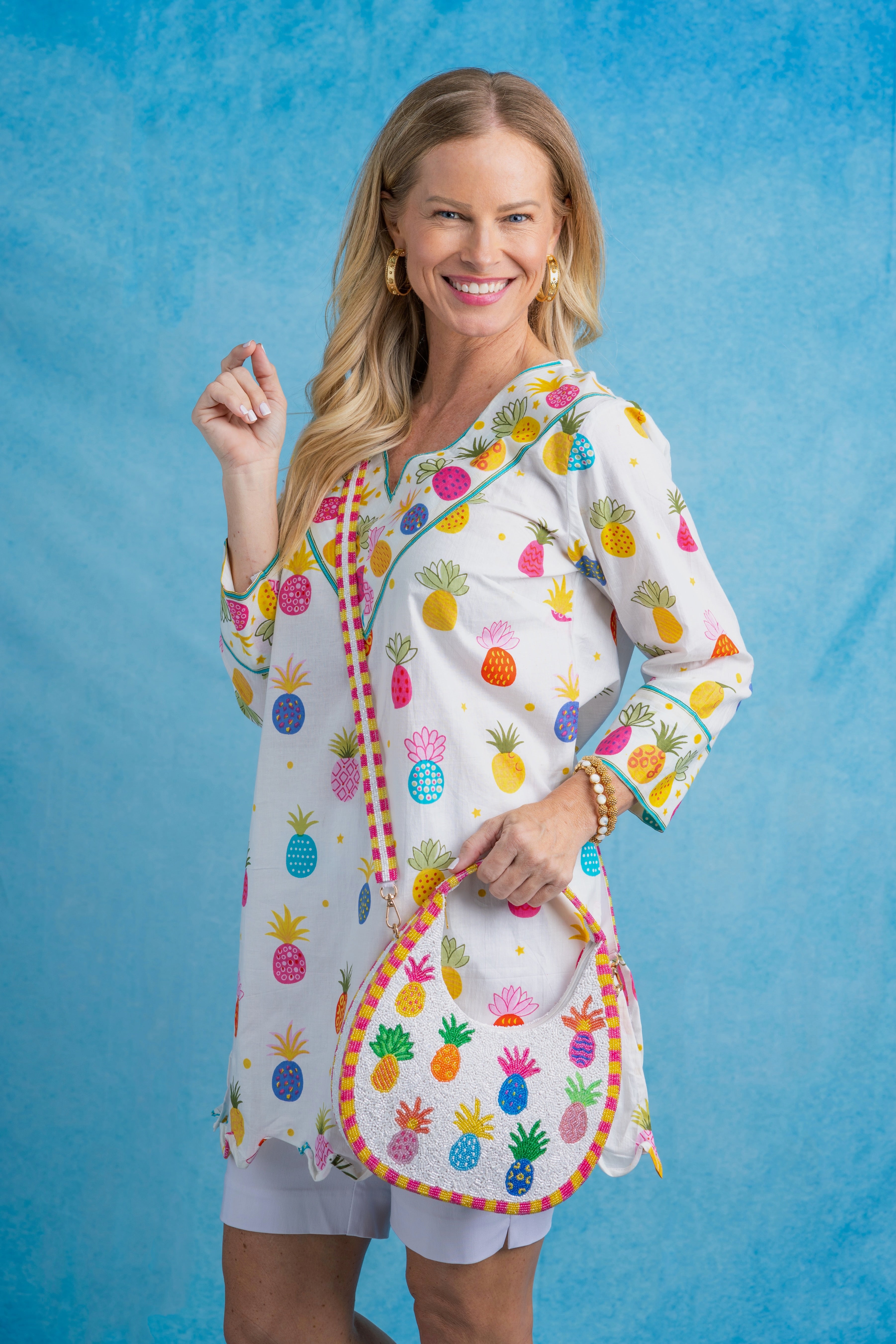 Woman wearing a colorful pineapple-patterned outfit against a blue background